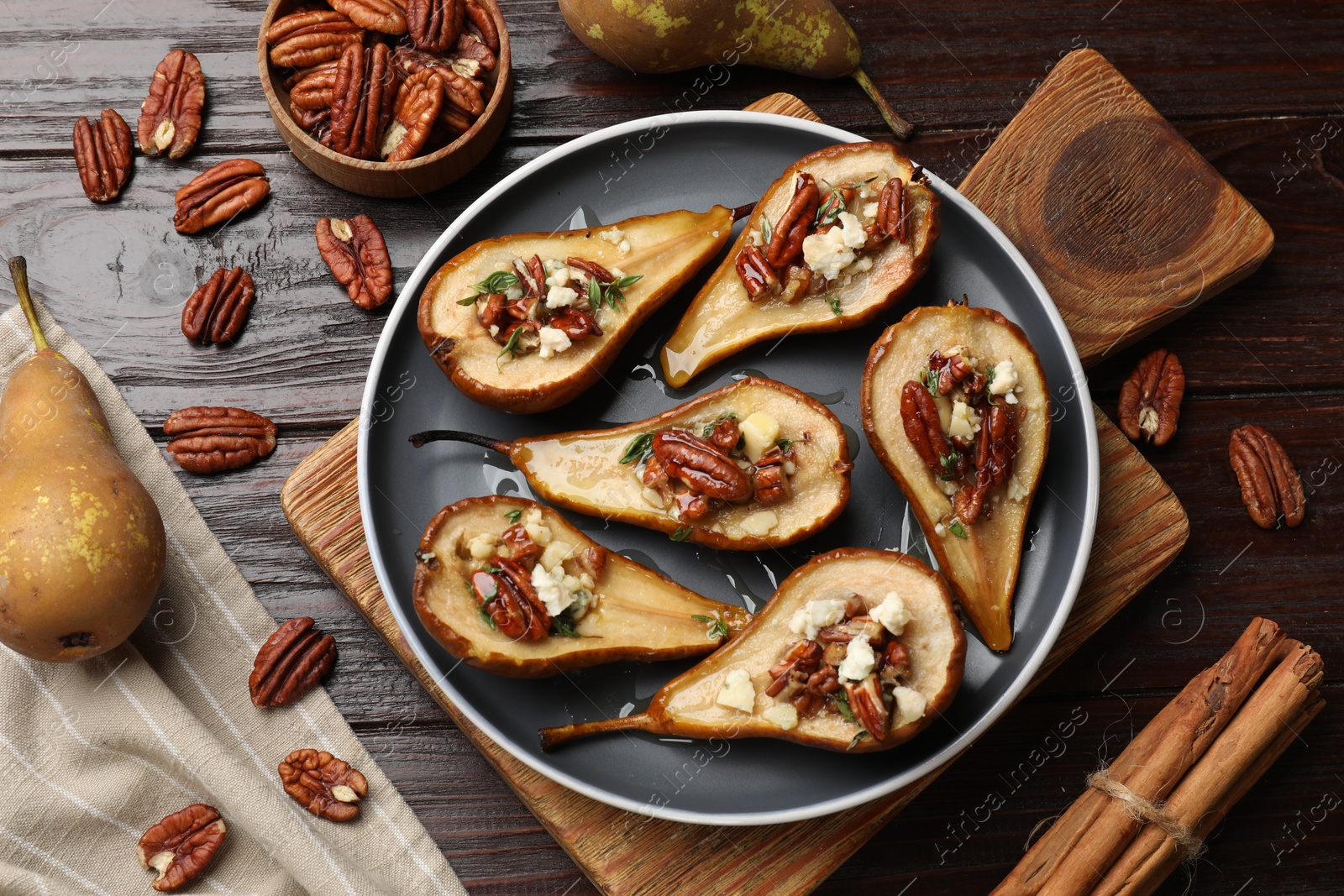 Photo of Delicious baked pears with nuts, blue cheese and honey on wooden table, flat lay