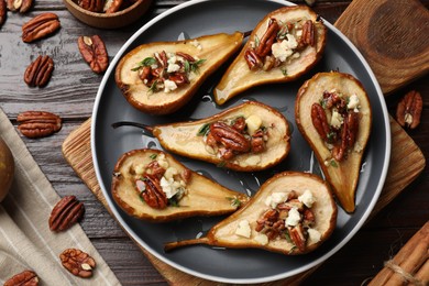 Photo of Delicious baked pears with nuts, blue cheese and honey on wooden table, flat lay