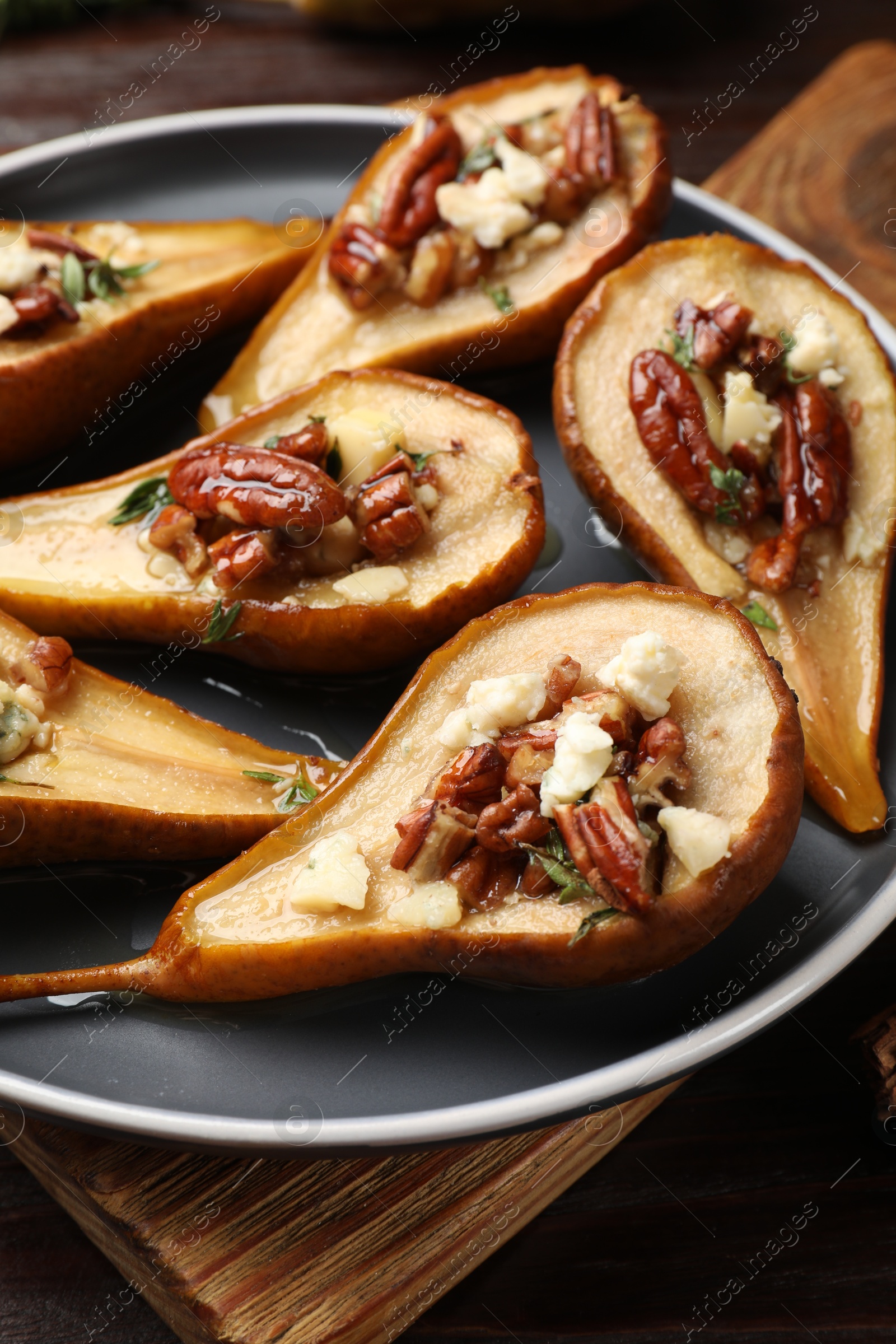 Photo of Delicious baked pears with nuts, blue cheese and honey on table, closeup