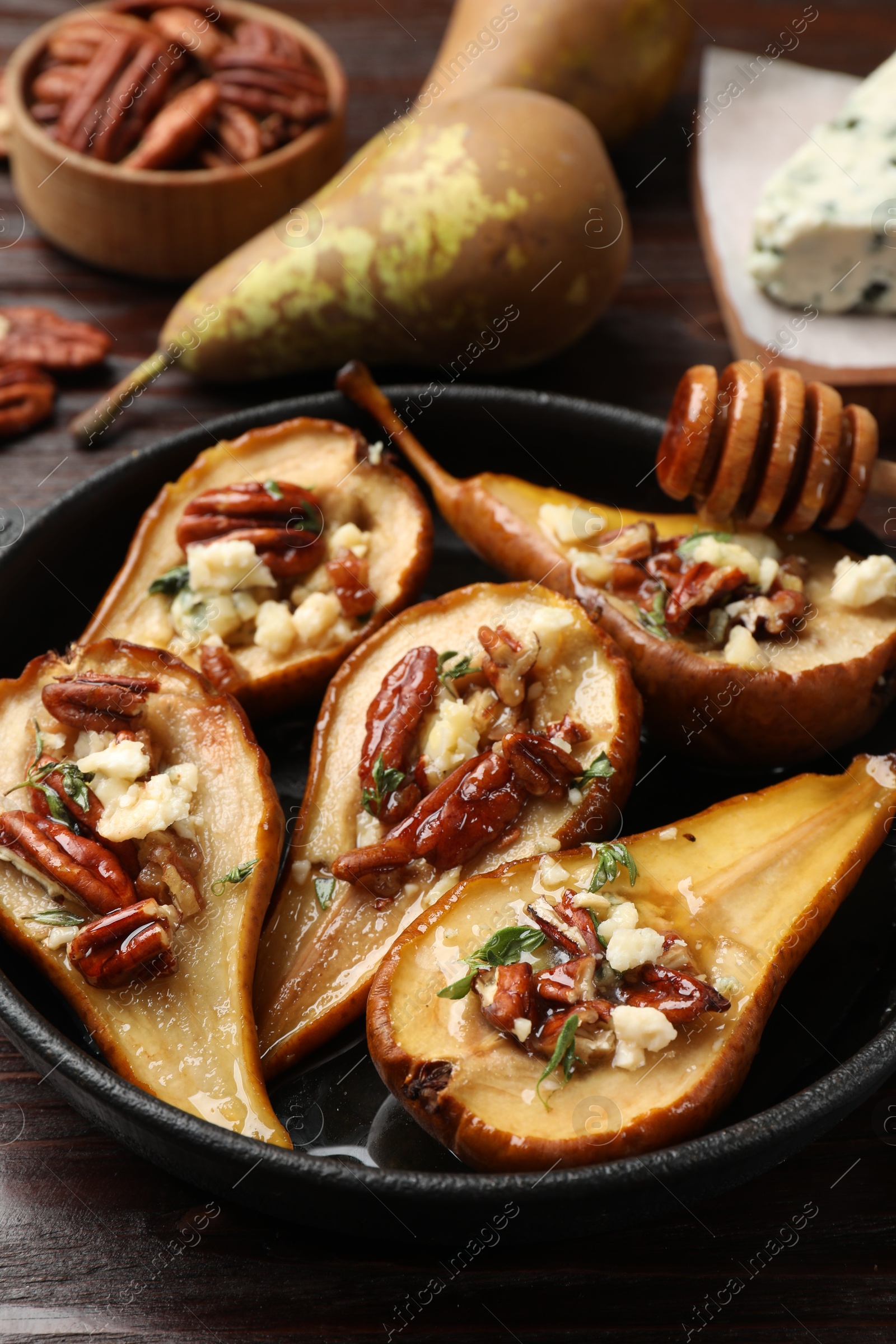 Photo of Delicious baked pears with nuts, blue cheese and honey on wooden table, closeup