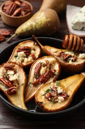 Delicious baked pears with nuts, blue cheese and honey on wooden table, closeup