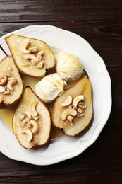 Delicious baked pears with nuts, ice cream and honey on wooden table, top view