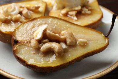 Delicious baked pears with nuts and honey on plate, closeup