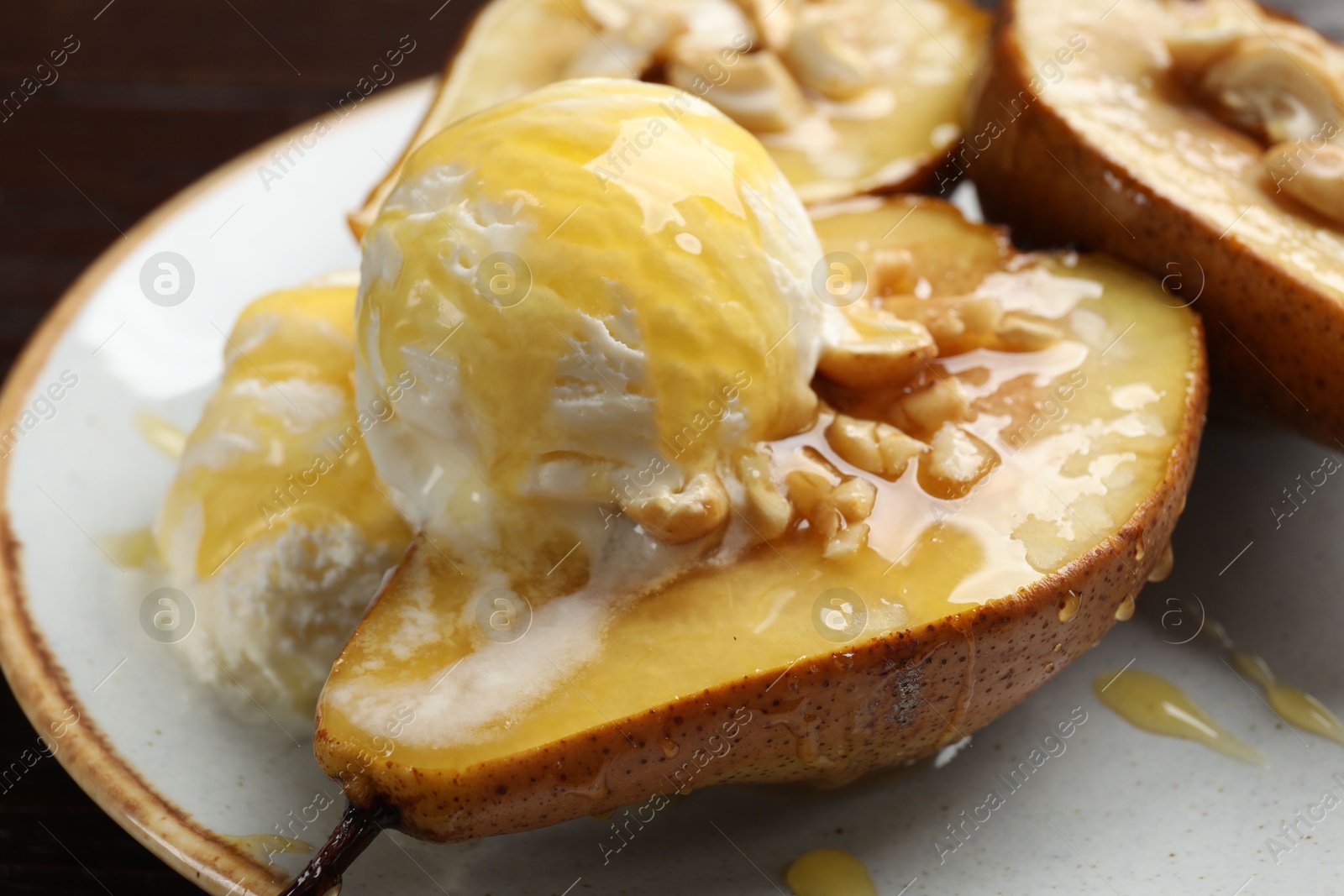 Photo of Delicious baked pears with nuts, ice cream and honey on plate, closeup