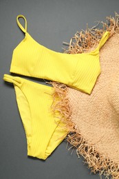 Yellow swimsuit and hat on grey background, flat lay