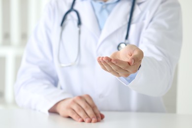 Photo of Doctor holding something at white table in clinic, closeup