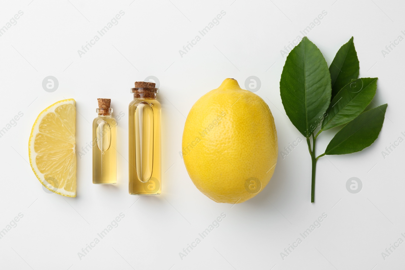 Photo of Bottles of essential oils, lemon and green leaves on white background, flat lay