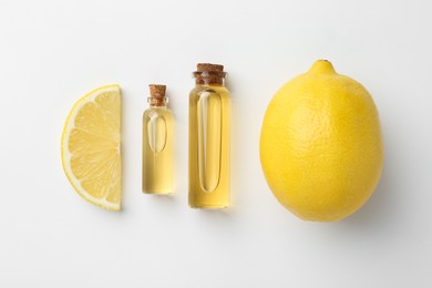 Bottles of essential oils and lemon on white background, top view