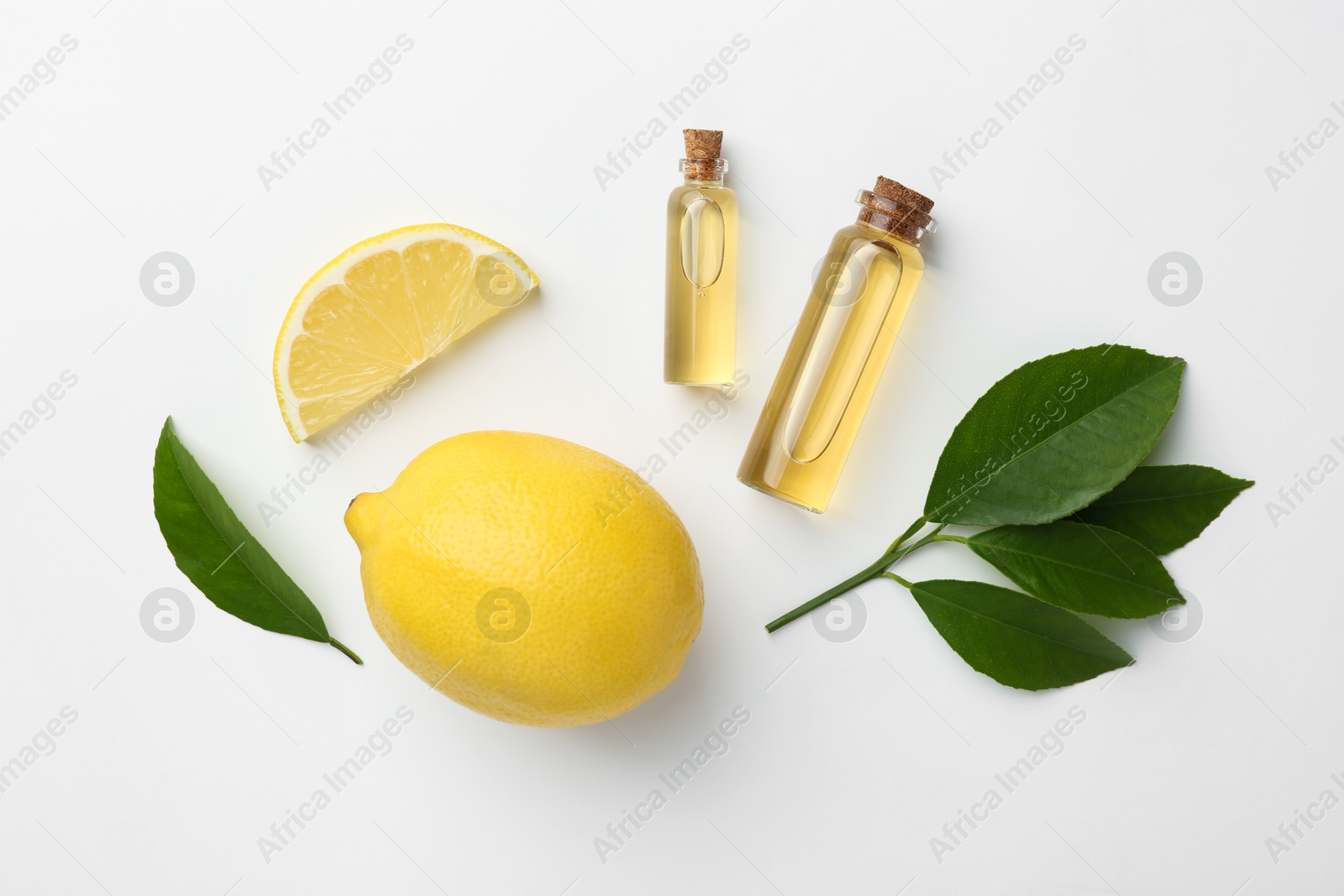 Photo of Bottles of essential oils, lemon and green leaves on white background, flat lay