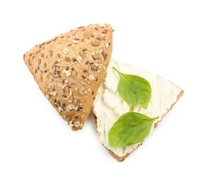 Photo of Pieces of bread with cream cheese and basil leaves isolated on white, top view