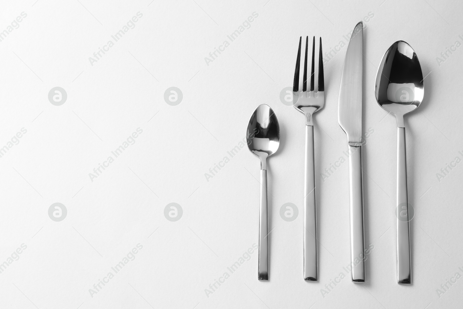 Photo of Stylish silver cutlery on white background, flat lay. Space for text