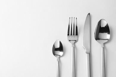 Photo of Stylish silver cutlery on white background, flat lay. Space for text