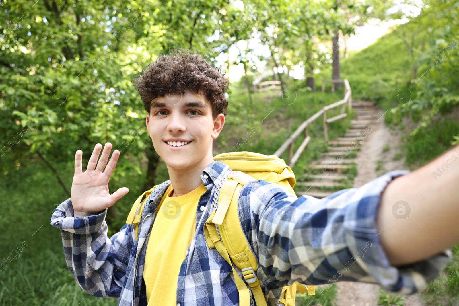 Photo of Smiling travel blogger with backpack takIng selfie outdoors