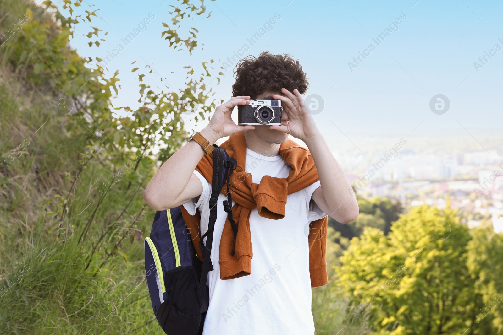 Photo of Travel blogger with vintage camera taking photo outdoors