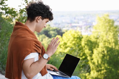 Travel blogger with laptop having online meeting outdoors