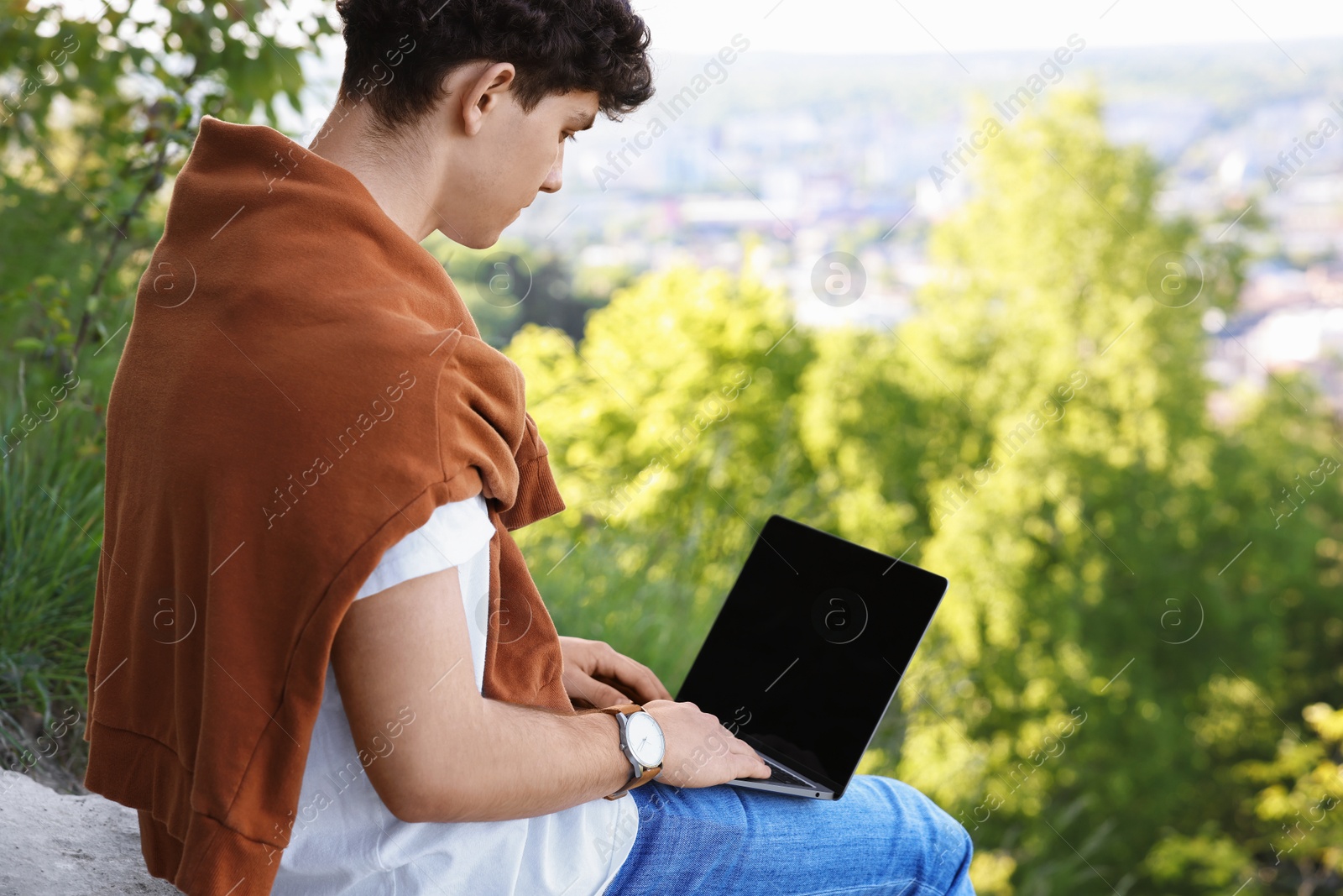 Photo of Handsome travel blogger using modern laptop outdoors