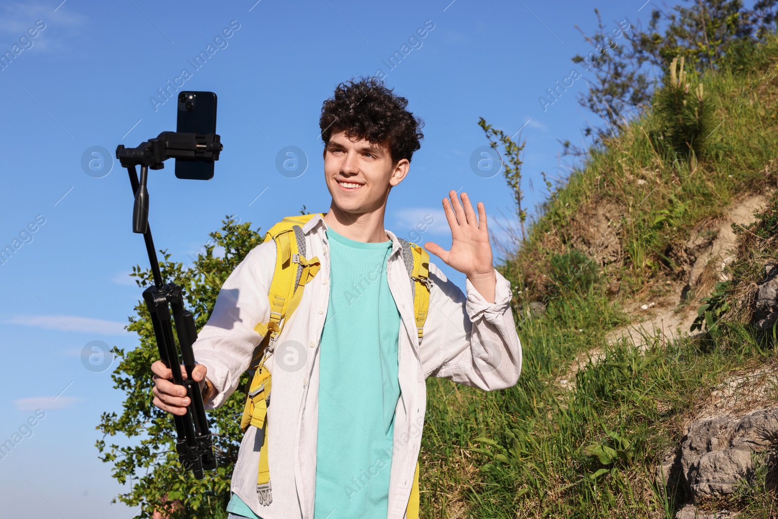 Photo of Travel blogger with smartphone and tripod streaming outdoors