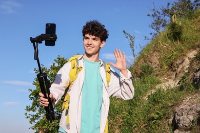 Travel blogger with smartphone and tripod streaming outdoors