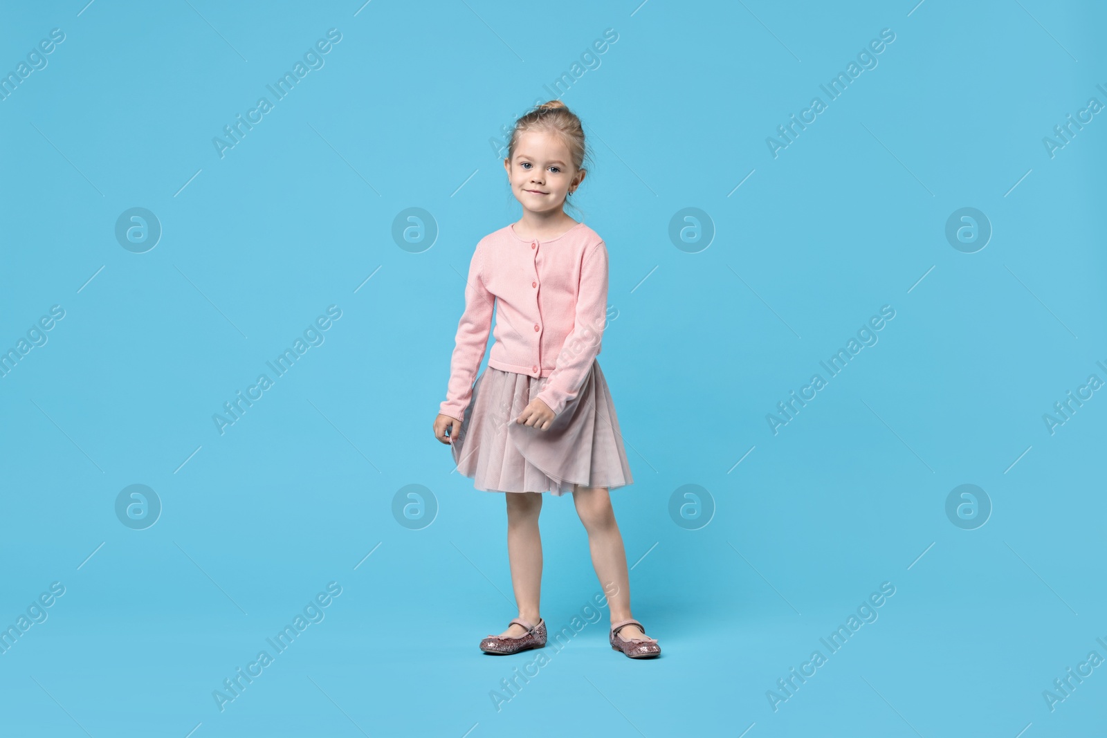 Photo of Cute little girl dancing on light blue background