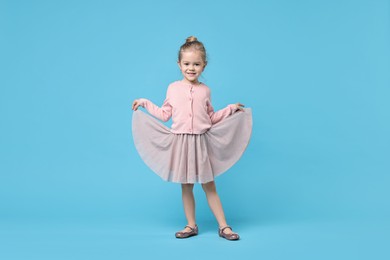 Cute little girl dancing on light blue background