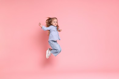 Cute little girl dancing on pink background, space for text