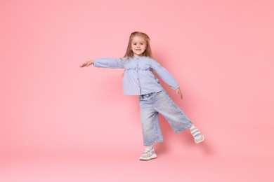 Cute little girl dancing on pink background