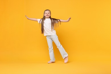 Cute little girl dancing on yellow background, space for text