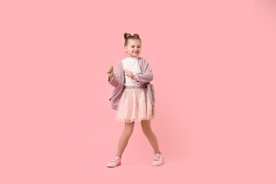 Cute little girl dancing on pink background
