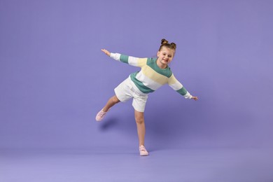 Cute little girl dancing on violet background