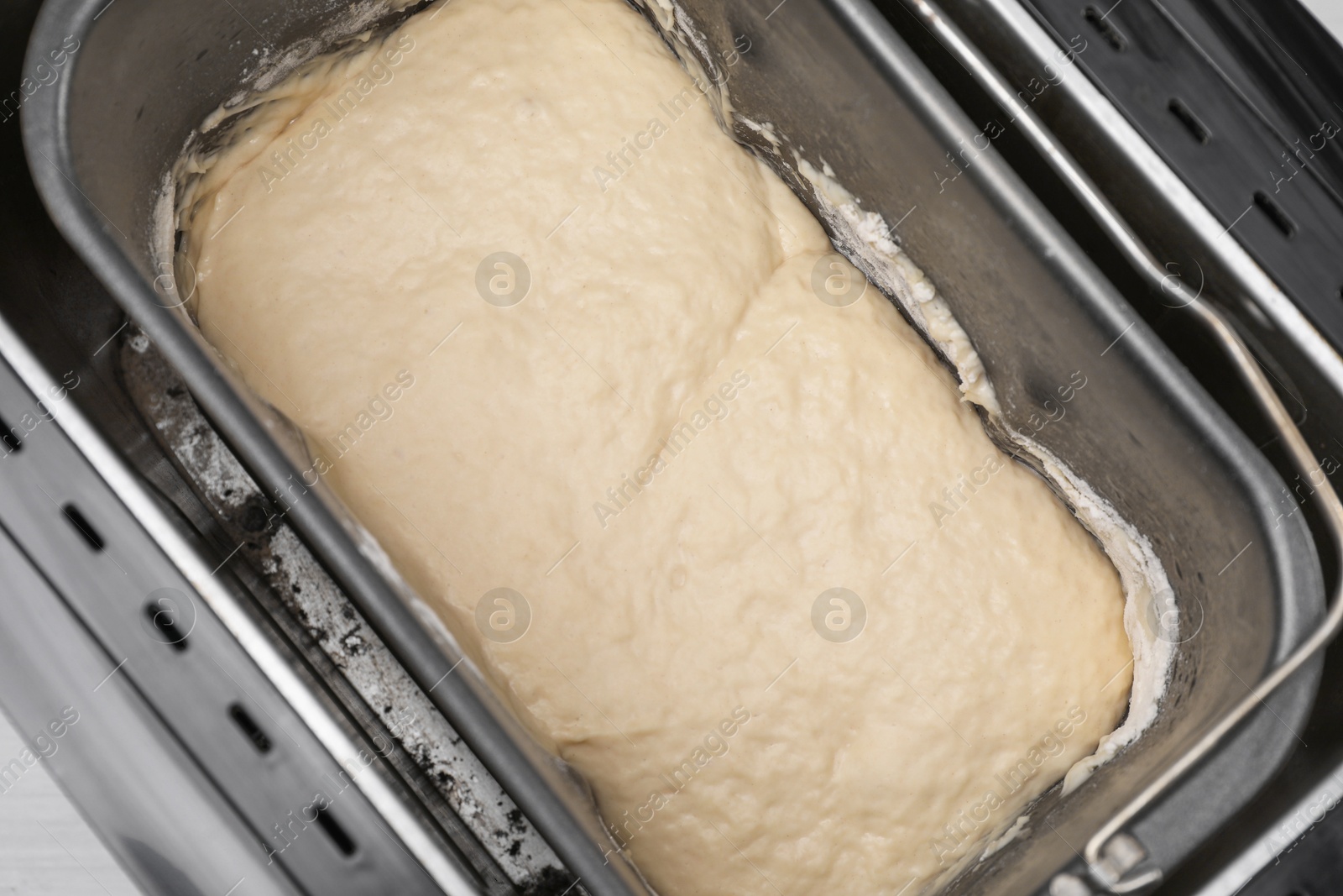 Photo of Breadmaker with raw dough on table, above view