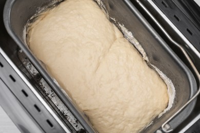 Breadmaker with raw dough on table, above view