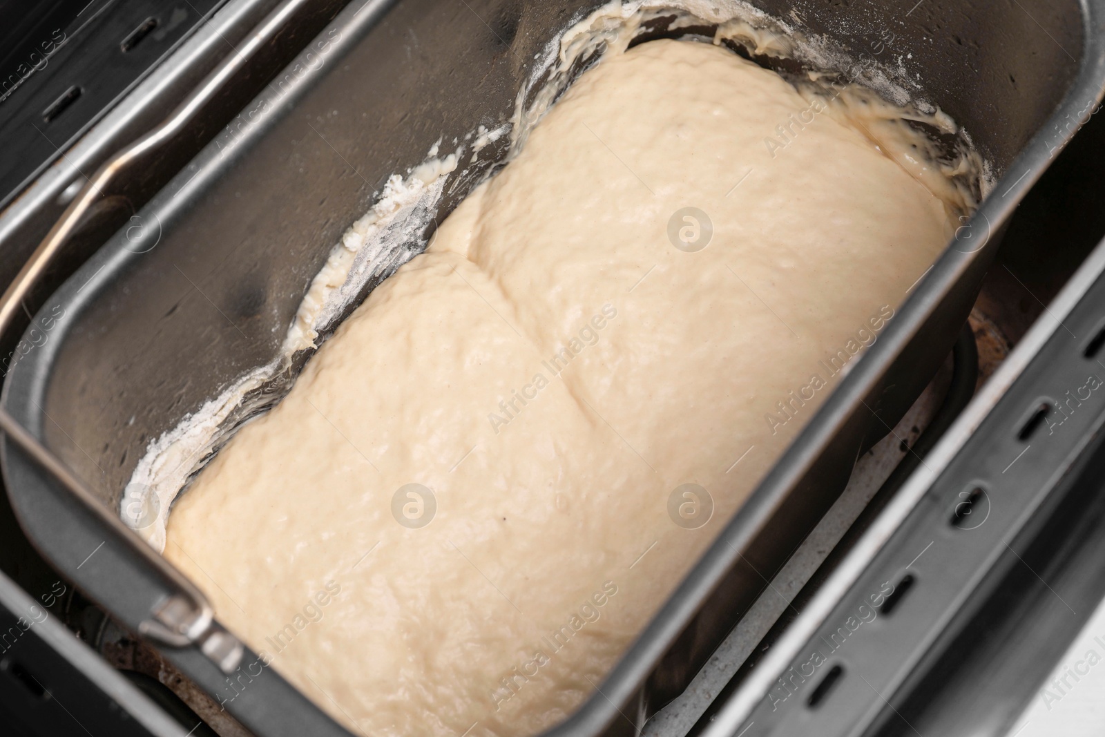 Photo of Breadmaker with raw dough on table, closeup