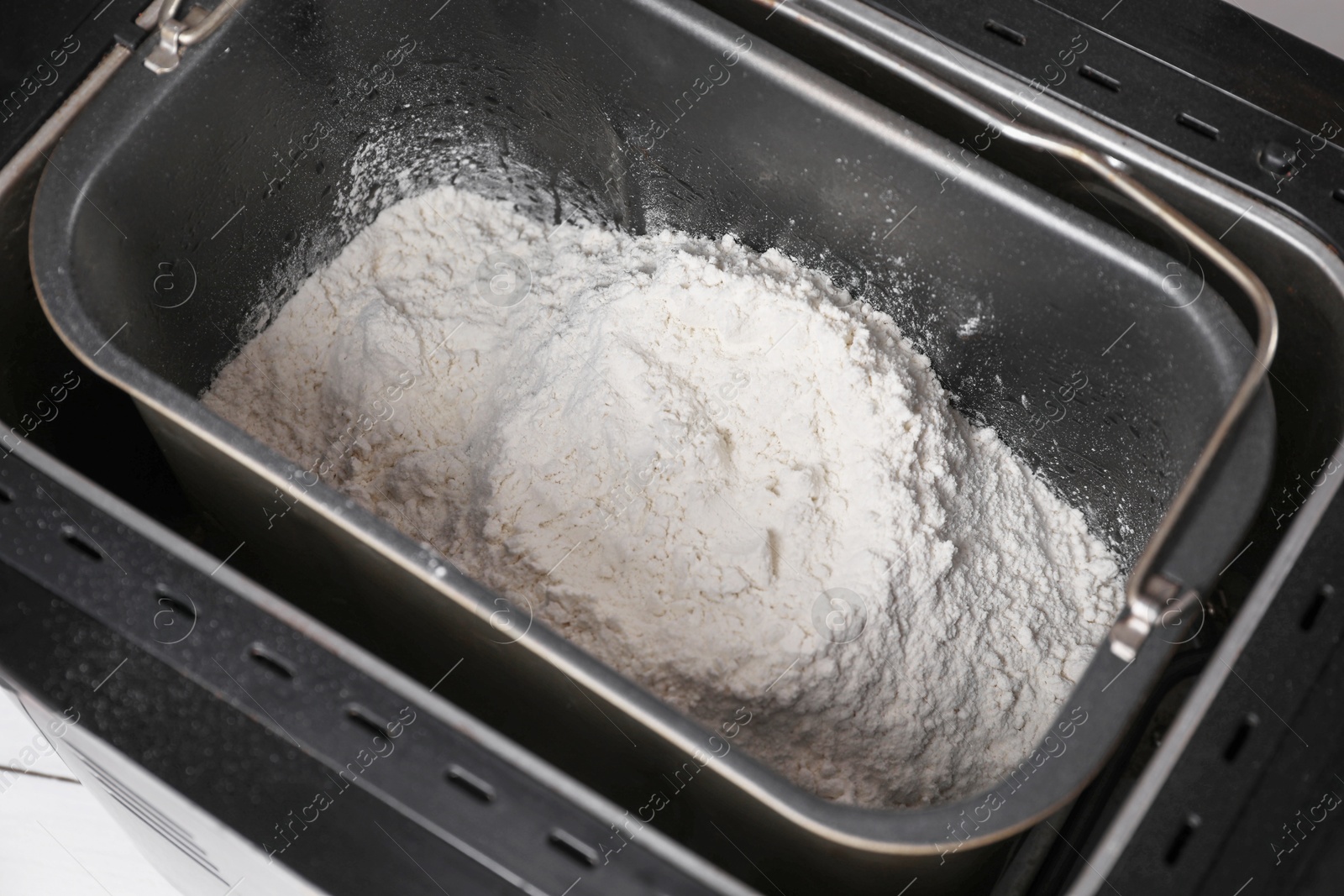 Photo of Modern breadmaker with flour on table, closeup