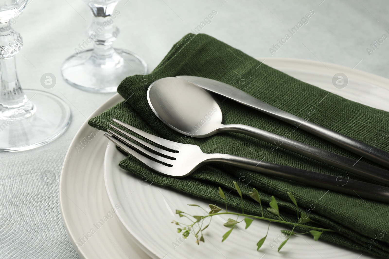 Photo of Stylish setting with cutlery, leaves and plates on table, closeup