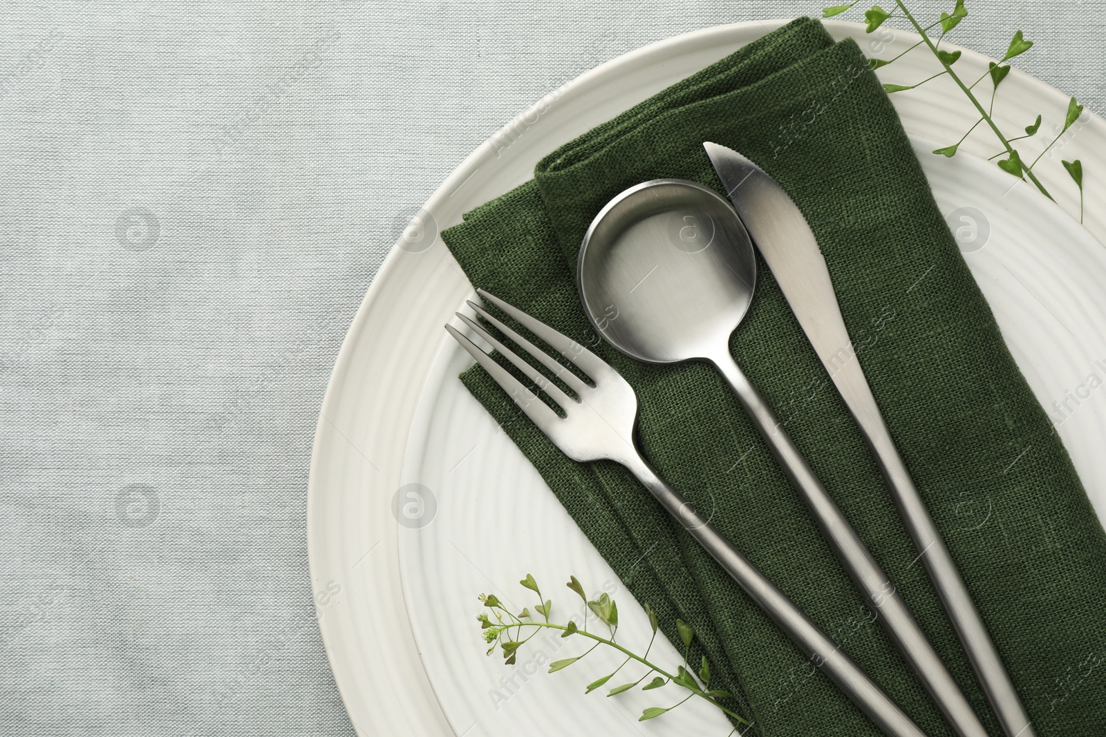 Photo of Stylish setting with cutlery, leaves and plates on grey table, top view. Space for text