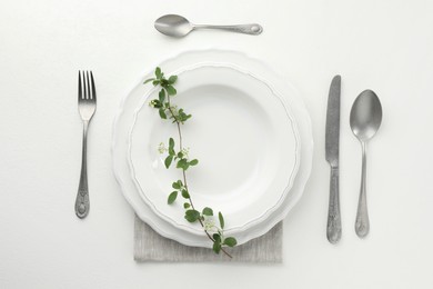 Photo of Stylish setting with cutlery and plates on white textured table, flat lay