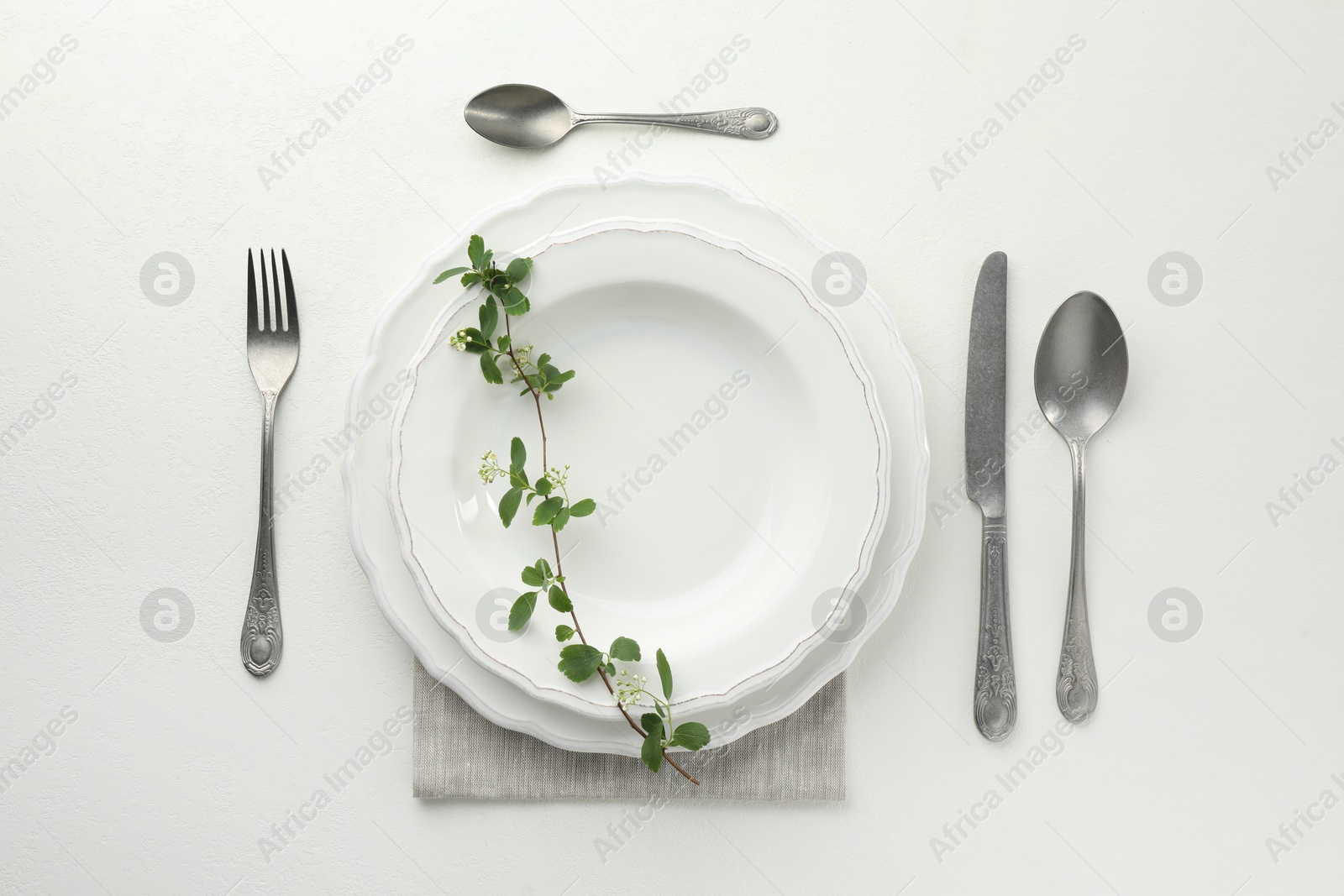 Photo of Stylish setting with cutlery and plates on white textured table, flat lay