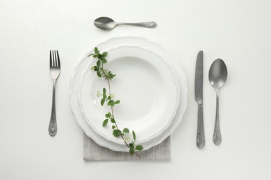 Stylish setting with cutlery and plates on white textured table, flat lay