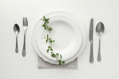 Stylish setting with cutlery and plates on white textured table, flat lay