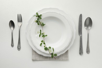 Photo of Stylish setting with cutlery and plates on white textured table, flat lay