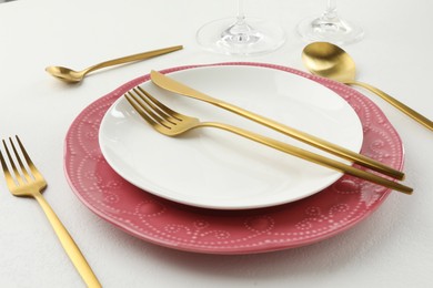 Photo of Stylish setting with cutlery and plates on white textured table, closeup