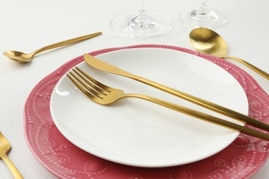 Photo of Stylish setting with cutlery and plates on white textured table, closeup