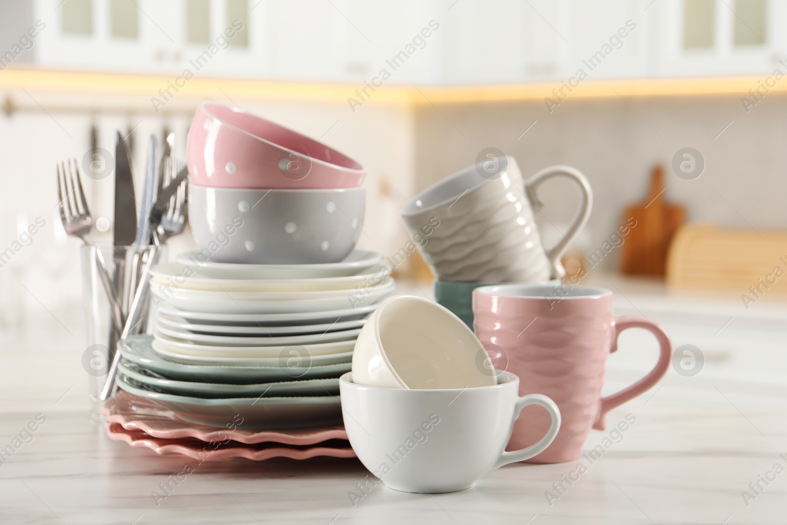 Photo of Many different clean dishware and cups on white marble table in kitchen