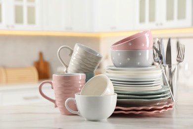 Photo of Many different clean dishware and cups on white marble table in kitchen. Space for text