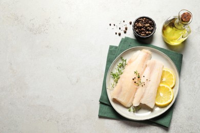 Photo of Plate with raw cod fish, spices, microgreens and lemon on grey textured table, flat lay. Space for text