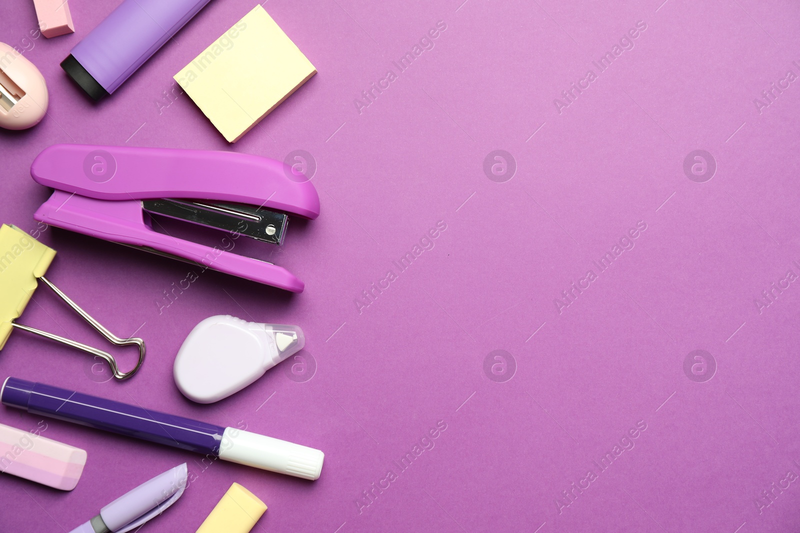 Photo of Flat lay composition with stapler and different stationery on violet background, space for text