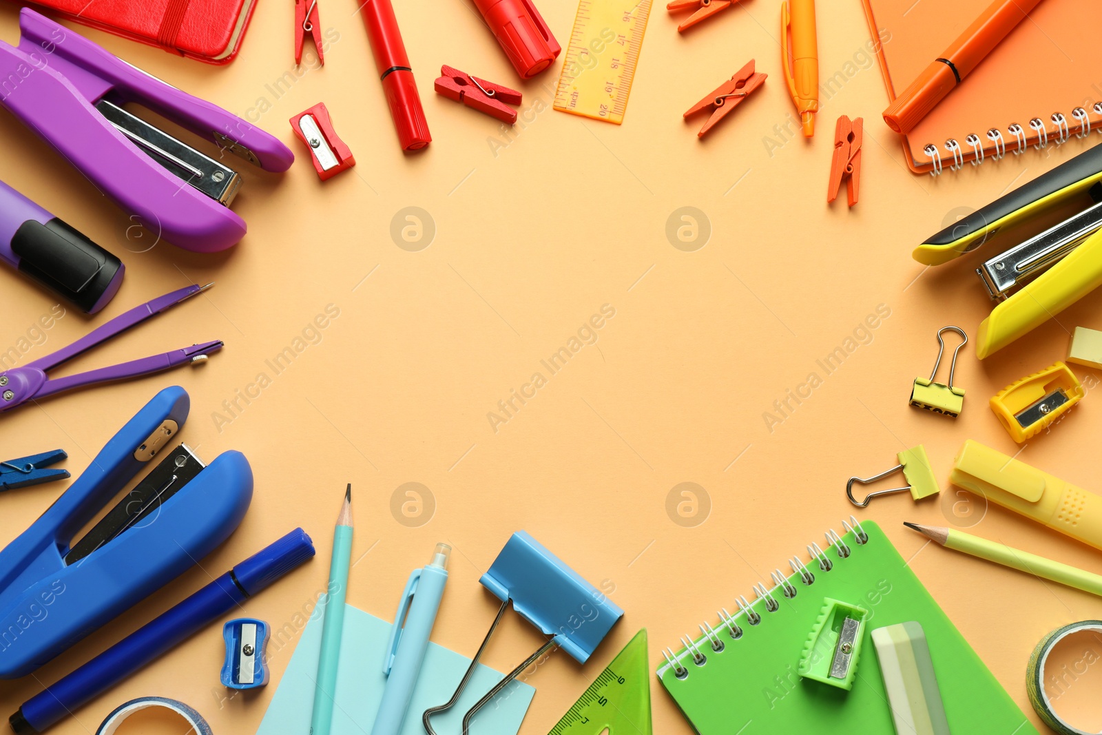 Photo of Flat lay composition with notebook, stapler and different stationery on pale orange background, space for text