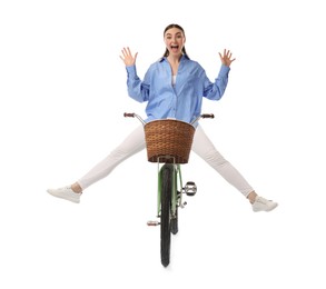 Emotional woman having fun while riding bicycle with basket against white background
