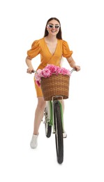 Photo of Smiling woman in sunglasses riding bicycle with basket of peony flowers on white background