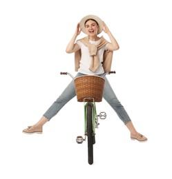 Smiling woman having fun while riding bicycle with basket on white background